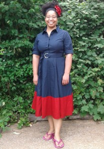 Roshaunda in a retro style navy and red dress, red flower hair pin, and pink flip-flops